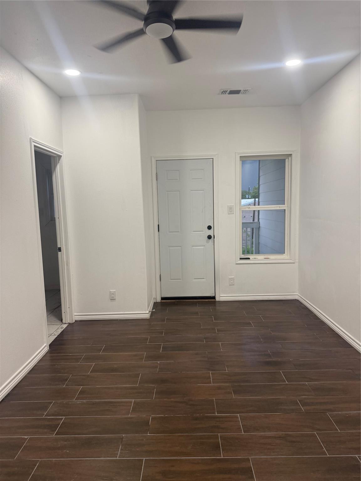 Bright living room with ceiling fan and door to the balcony
