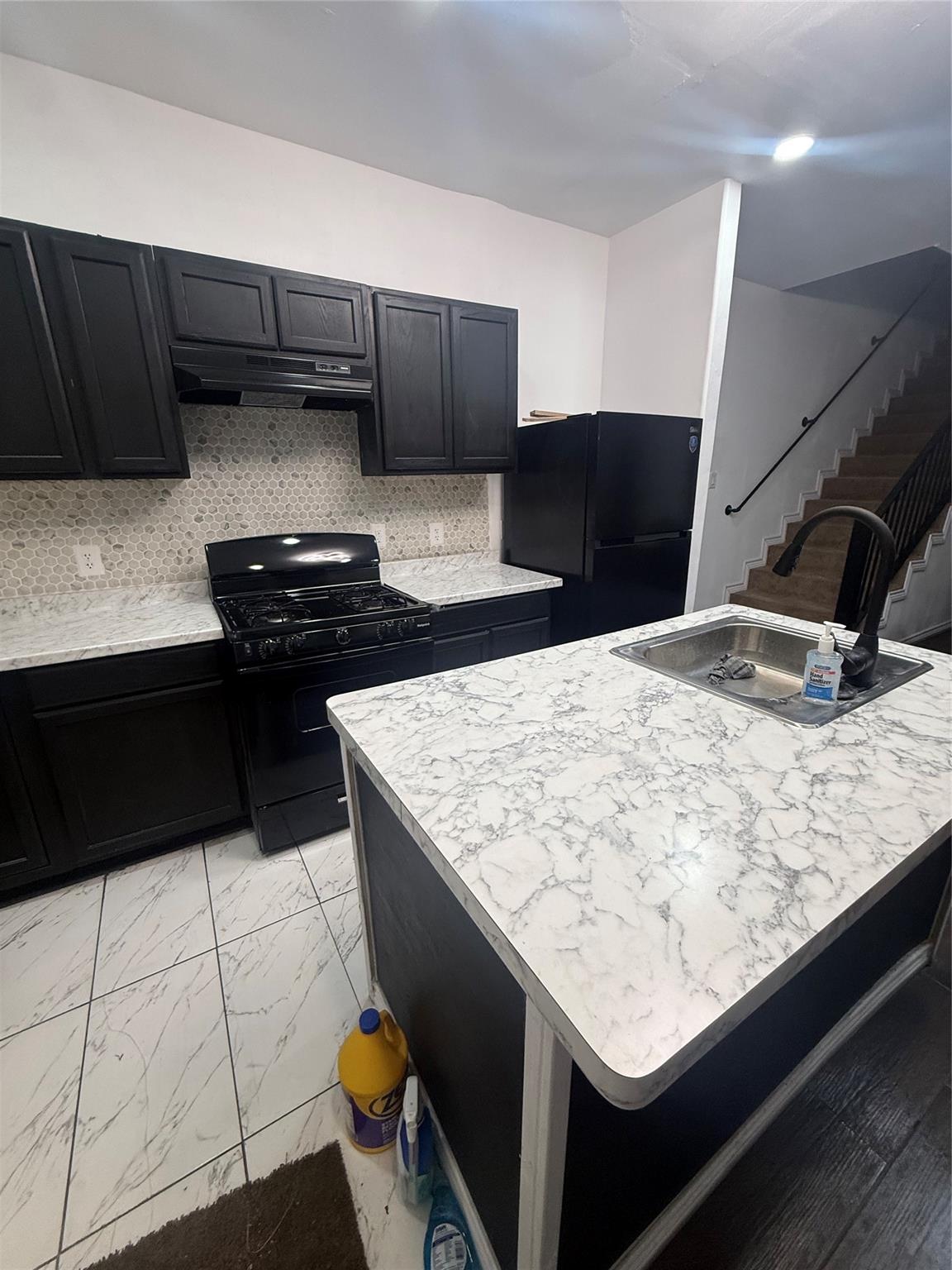 Shared kitchen with island sink, gas stove, refrigerator and dishwasher